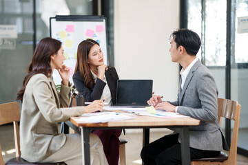 Group of Asian businesspeople sits down for a business investment planning meeting.