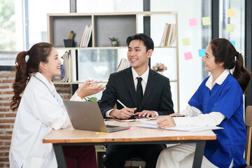 A lone Asian male doctor is working in a hospital conference room.