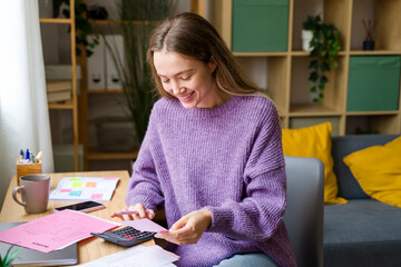 Woman planning personal budget with calculator at home