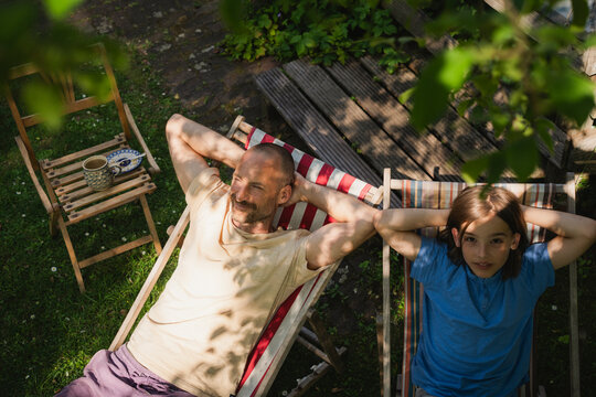 Father and son relaxing on deck chairs in sunny summer garden