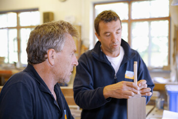 Carpenter instructing apprentice in woodwork at workshop in Schaeftlarn