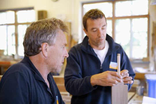 Carpenter instructing apprentice in woodwork at workshop in Schaeftlarn