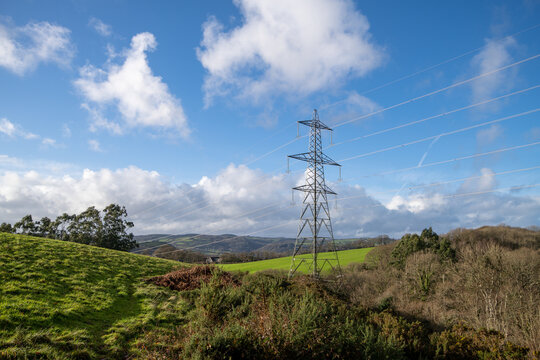 Devonshire countryside with rolling green fields and blue skies. Electricity pylons cross the landscape. Hiking and country walks. English rural landscape.