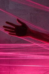 Hand reaches through pink laser beams in abstract artistic studio shot