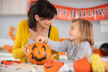 Fototapeta premium a mother and her daughter carving pumpkins for halloween