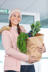 young girl holding paper bag of groceries from supermarket