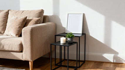 Modern living room corner with beige sofa, black nesting tables, candle, potted plant, and framed artwork