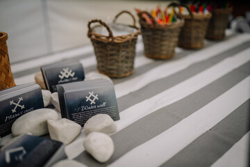 Riga, Latvia - December 19, 2025: Decorative baskets filled with colorful items on a striped tablecloth alongside informational cards and smooth stones