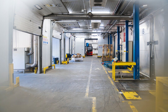 Cold storage warehouse interior with multiple loading docks, industrial refrigeration systems, and a forklift preparing for logistics operations