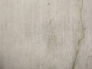 Obraz premium Detailed texture of a weathered grey concrete wall featuring a long vertical crack, subtle mossy stains, and a gritty industrial surface ideal for urban backgrounds and minimalist designs.