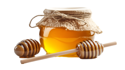 Golden jar of natural liquid honey sealed with a rustic burlap top and accompanied by two wooden dippers ready for serving this sweet golden substance in a clean presentation.
