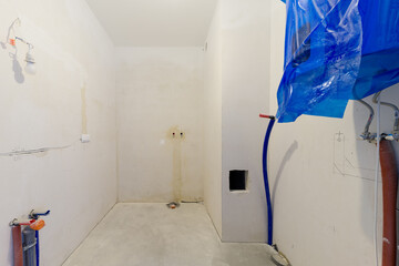 Unfinished bathroom interior with exposed pipes and wires