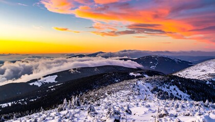 Snow-covered mountain range silhouetted against a vibrant sunset sky with golden hues and wispy clouds