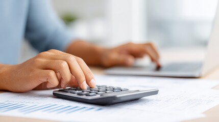 African American accountant using a calculator while working on financial documents at a desk with a laptop, illustrating the concept of financial analysis and management