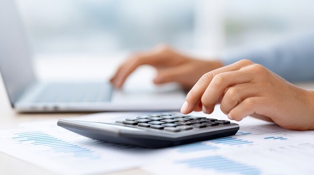 Accountant using calculator and laptop, analyzing financial data on documents, showcasing professional workspace with graphs and charts for business analysis - Powered by Adobe