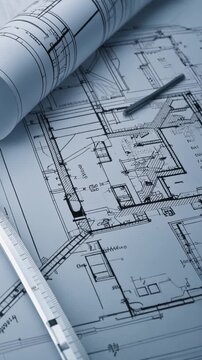 Architectural blueprints and drafting tools on a table.