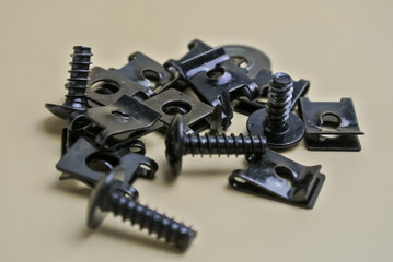 Close-up of black metal screws and spring clips scattered on a surface
