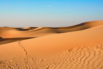 Sunset over the desert of Al Khatim in Abu Dhabi, Emirates. Golden Sand Dune Desert Landscape Panorama. Beautiful sunset over the sand dunes