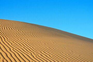 Sunset over the desert of Al Khatim in Abu Dhabi, Emirates. Golden Sand Dune desert landscape dunes with blue sky. Sand mounds formed in circular shape, beauty of natural changes over great stretches