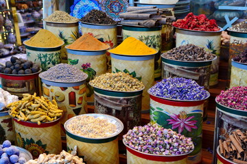 arabian spice and herb street market stall. Traditional spices market. Pots and wooden tubs stand in row with colorful tea, spices, fruits, roots, flowers. Street bazaar. Dubai, UAE.