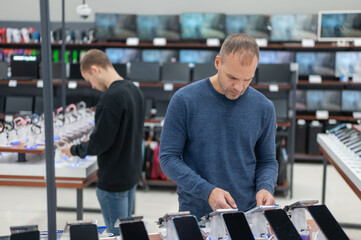 Two Caucasian men are choosing a smartphone in a store.