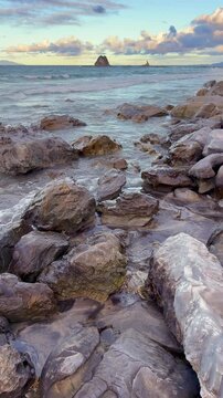 Peaceful ocean waves hitting rocks at Mangawhai Heads beach, New Zealand. Vertical video capturing a calm coastal landscape, ideal for meditation, relaxation, mindfulness, and reflective moments.