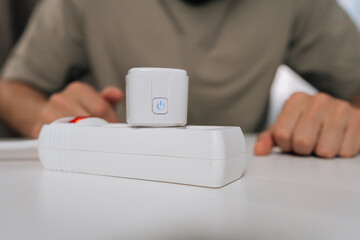 Person setting up smart home technology, connecting smart plug into power strip, demonstrating energy management, automation and remote control for modern household.
