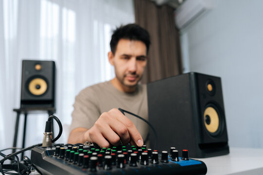 Focus on foreground of professional audio engineer tuning mixing console, setting up sound system with professional studio monitor speakers for music production session, selective focus.