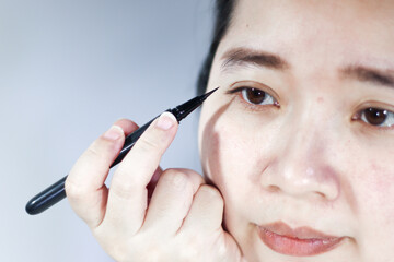 A woman is using eyeliner on her eyelid