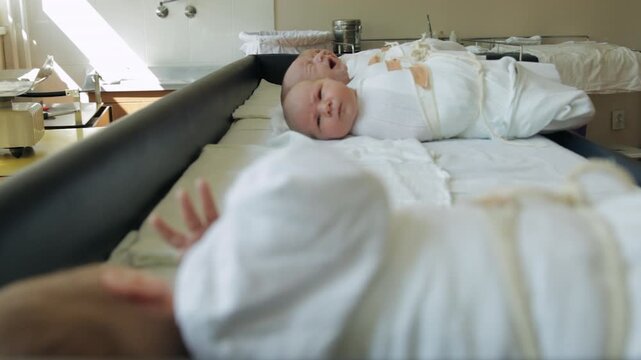 Swaddled newborn babies on hospital bassinet in nursery maternity ward