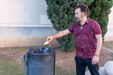 Latino man recycling paper coffee cup in urban park, promoting sustainability
