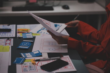 Team of uxui designers pointing at computer screen, discussing new mobile app design in the office