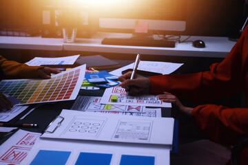 Team of uxui designers pointing at computer screen, discussing new mobile app design in the office