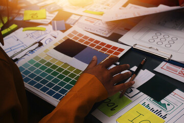 Team of uxui designers pointing at computer screen, discussing new mobile app design in the office