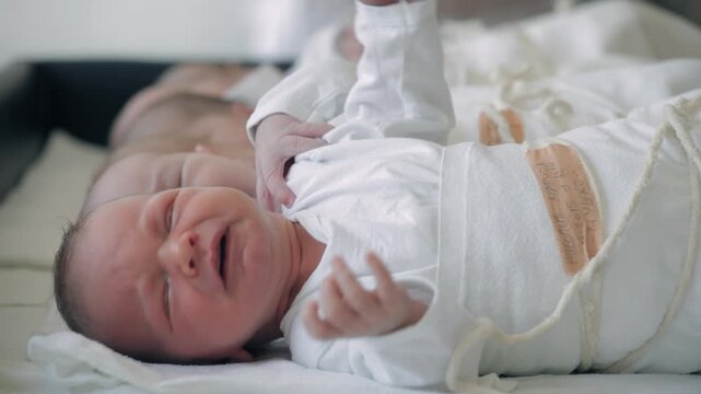 Crying newborn baby in hospital bassinet, group of infants in background