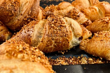Crunchy croissants with layered dough and nut topping, arranged on a baking sheet. Warm bakery atmosphere and fresh pastry concept.