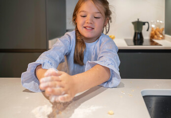 Happy girl playing with flour on kitchen counter