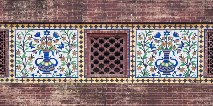 Colorful kashi-kari or faience tile mosaic floral design panels and sandstone jali on ancient mughal Wazir Khan mosque, Lahore, Punjab, Pakistan