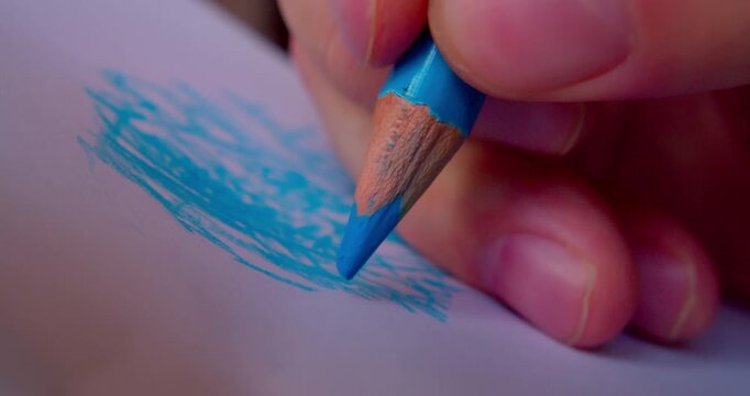 Close-up shot of hand drawing abstract pattern on paper with blue pencil