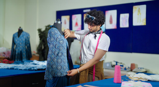 Indian happy young adult gen z male man wear tape around neck do work good indoor class room. Smart teen pupil boy do create new dummy dress clothe craft learn skill course day college place