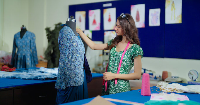 Indian young adult gen z lady female wear tape around neck learn new fashion design course indoor class room focused tailor pupil girl do create dummy dress cloth craft skill day inside college place