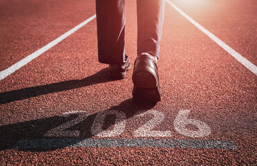Businessman walking forward with number 2026 displayed on running track. Concept of starting new year for career growth, and planning setting goals and key performance indicators (KPIs) in year 2026.