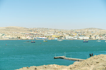 Colorful colonial buildings in Lüderitz, a small coastal town in Namibia, facing the Atlantic Ocean. Historic German architecture contrasts with desert landscapes, harbor views. © coffeinlix 