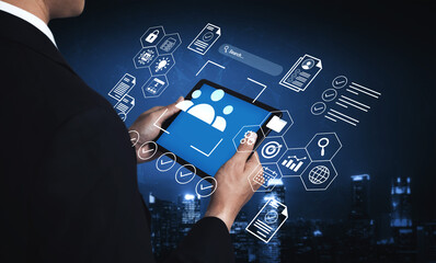 A business professional interacts with a tablet showcasing a digital interface filled with various icons and graphs, illustrating modern data analysis and cloud computing. Gantry