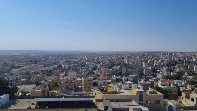 Wide cityscape view of Madaba, Jordan, captured on a sunny day, showing low-rise buildings stretching toward the horizon in one of the world&rsquo;s oldest continuously inhabited cities
