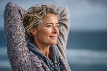 Middle-aged woman enjoying the refreshing ocean breeze with hair flowing freely by the seaside