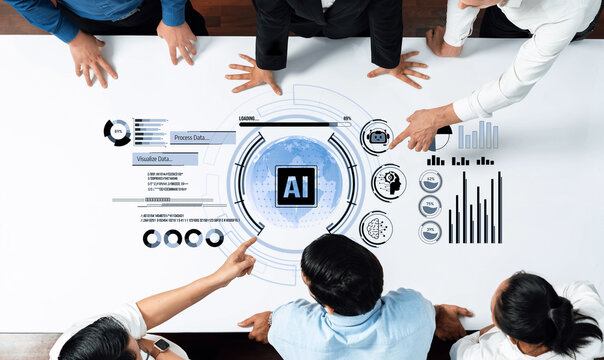 A diverse business team engages in discussion over AI data visualizations on a large table, highlighting teamwork and analysis in a modern office setting. Trope - Powered by Adobe