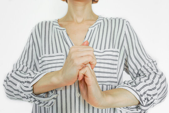 Woman grasping one hand with the other, demonstrating a self-massage and finger-stretching technique. Symbolizes muscle relaxation, tension release exercise, and circulation stimulation method.