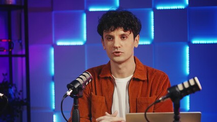 Male blogger recording finance podcast in studio, talking about investments