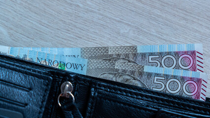 Polish 500 Zloty Banknotes Emerging from Black Leather Wallet on Wood